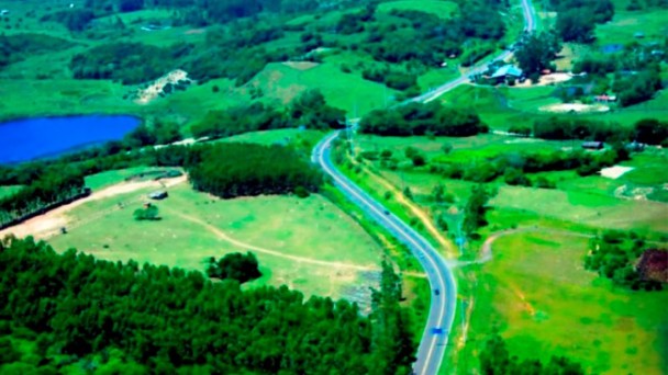 Foto área da da ERS-389, conhecida como Estrada do Mar, mostrando a rodovia e um grande área verde no entorno.