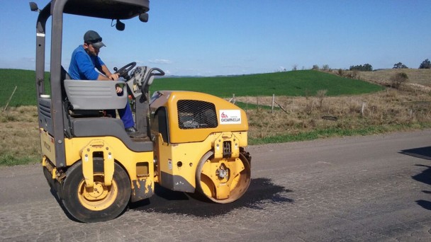 Na foto, um rolo compressor passa por um trecho de estrada durante obras de tapa-buraco.