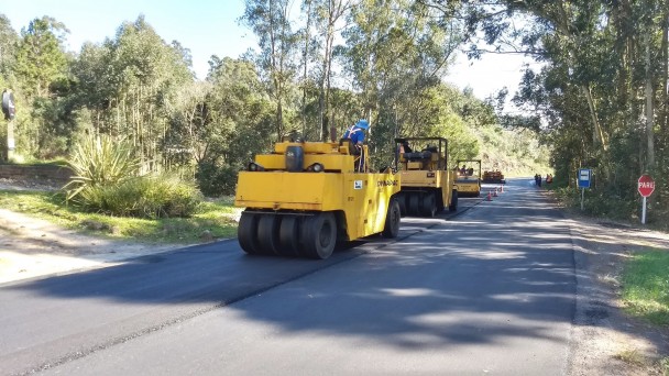 A foto mostra máquinas e operários em atividade nas obras de recuperação asfáltica da ERS-500, entre Sobradinho e Candelária. Uma via da estrada está recebendo amada nova de asfalto.