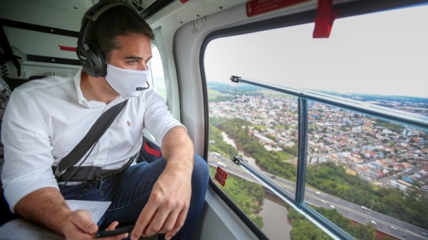 A foto mostra o governador no helicoptero olhando do alto as obras da ERS-118.