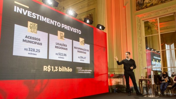 Na foto está o governador Eduardo Leite, vestindo uma roupa inteiramente preta, apresentando o plano de obras deste ano. 