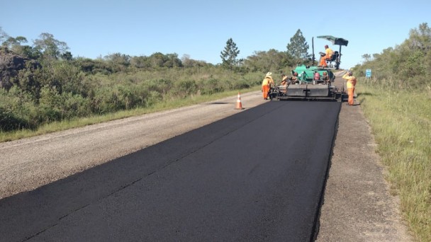 A imagem mostra máquinas realizando a compactação da pista