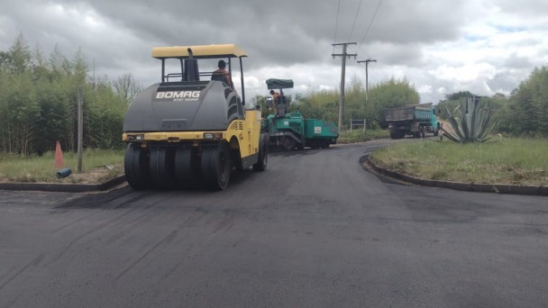 A imagem mostra máquinas realizando a compactação da pista