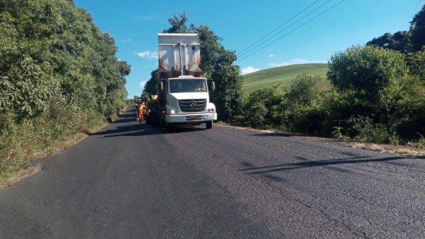 Imagem mostra caminhão despejando a nova camada do pavimento sobre a pista