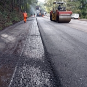 Imagem mostra máquinas durante a aplicação e compactação do novo asfalto
