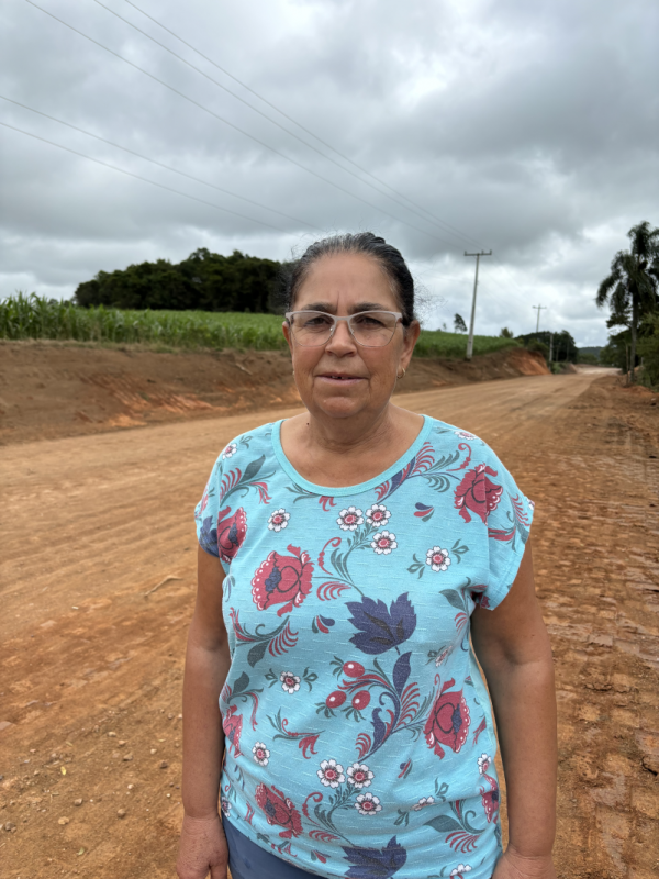 Imagem de mulher com camiseta de fundo azul com flores, está na estrada em obras