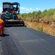 Imagem mostra m&aacute;quina de asfalto e homens trabalhando